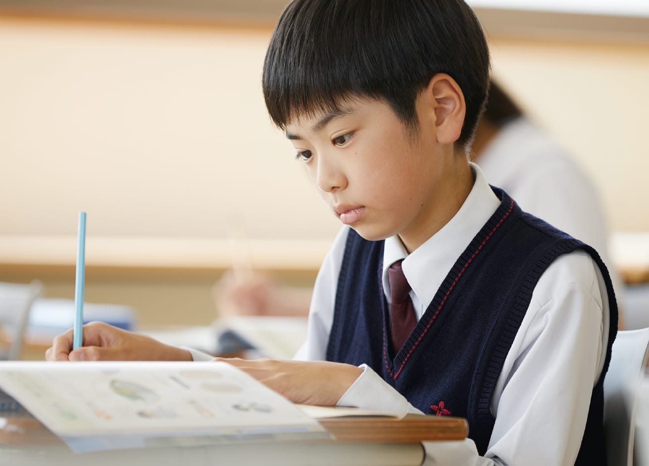 小学生の男の子が机に向かって教科書を見ながら、真剣に授業を受けている